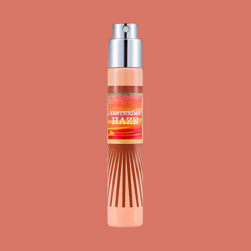 White Imaginary Authors travel spray with a peach and orange striped Yesterday Haze label on a coral background