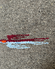 Close-up of a red and light blue thunderbird woven into charcoal wool