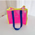 Hot pink mesh beach tote with neon yellow trim and blue handles on a table