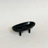 Black cast iron canoe-shaped incense burner on short legs on a white surface