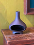Dark charcoal ceramic chiminea incense holder on a wood table against a yellow wall