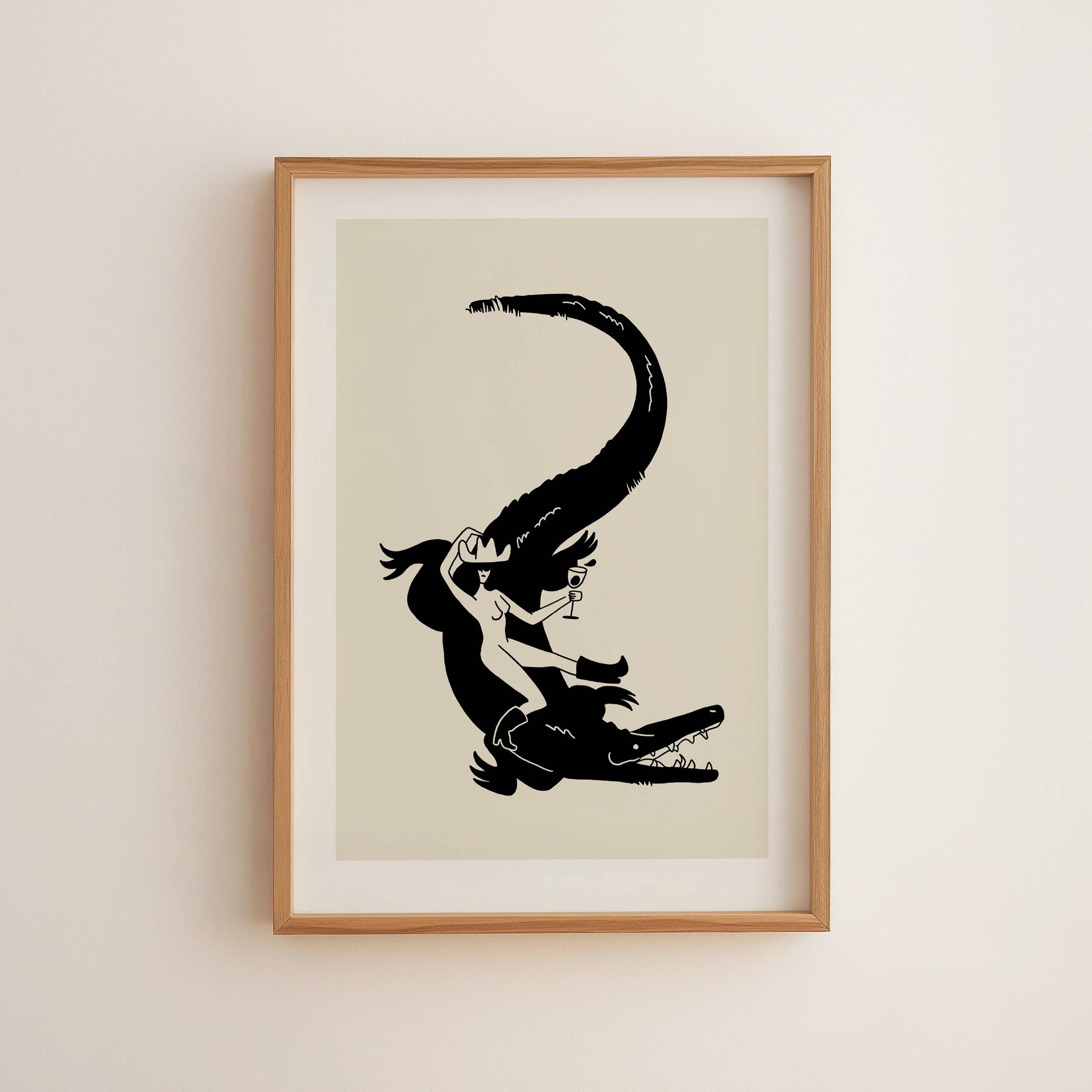 Framed artwork of a black silhouette of a woman and crocodile on a beige background