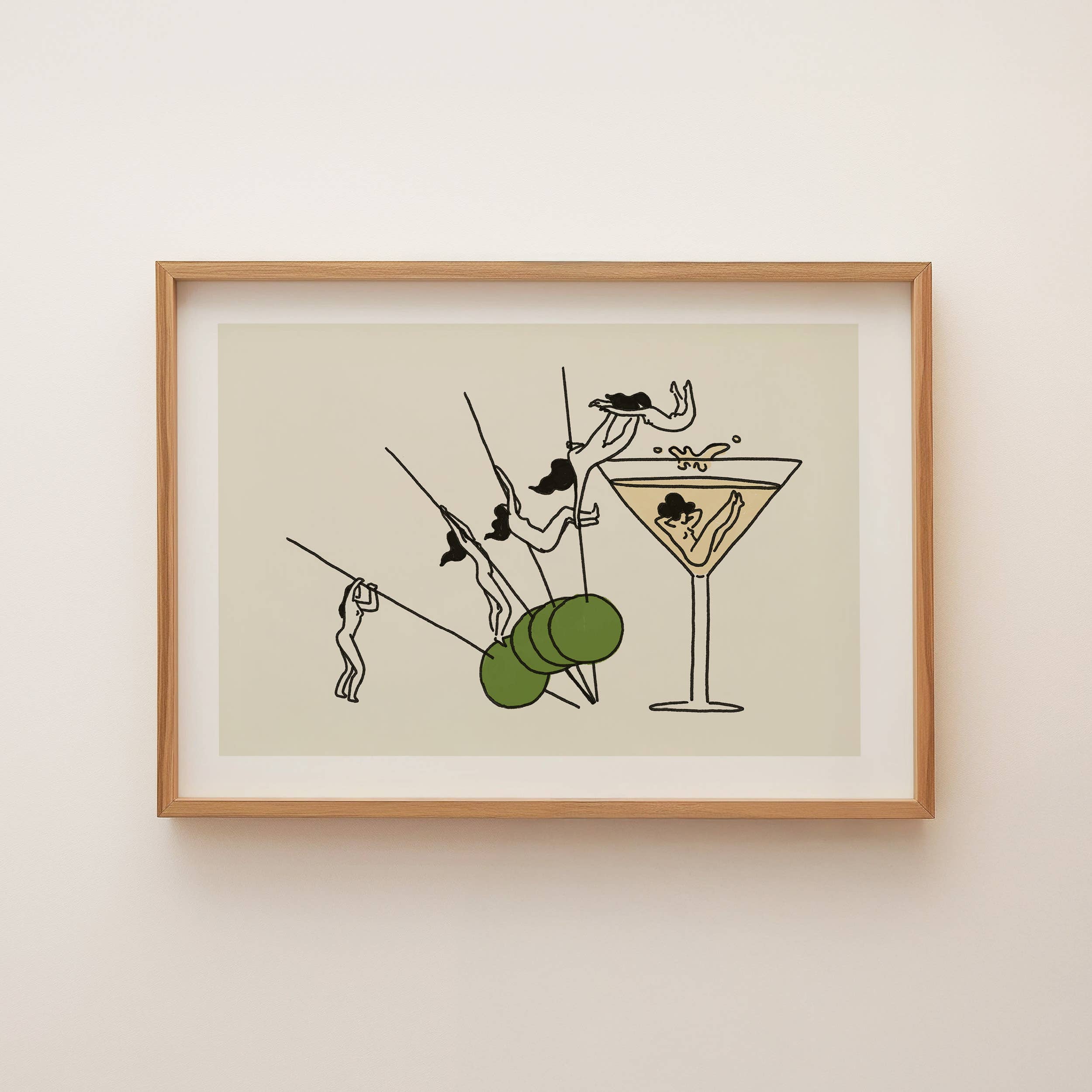 Framed artwork of a cocktail glass with a martini olive on a beige background
