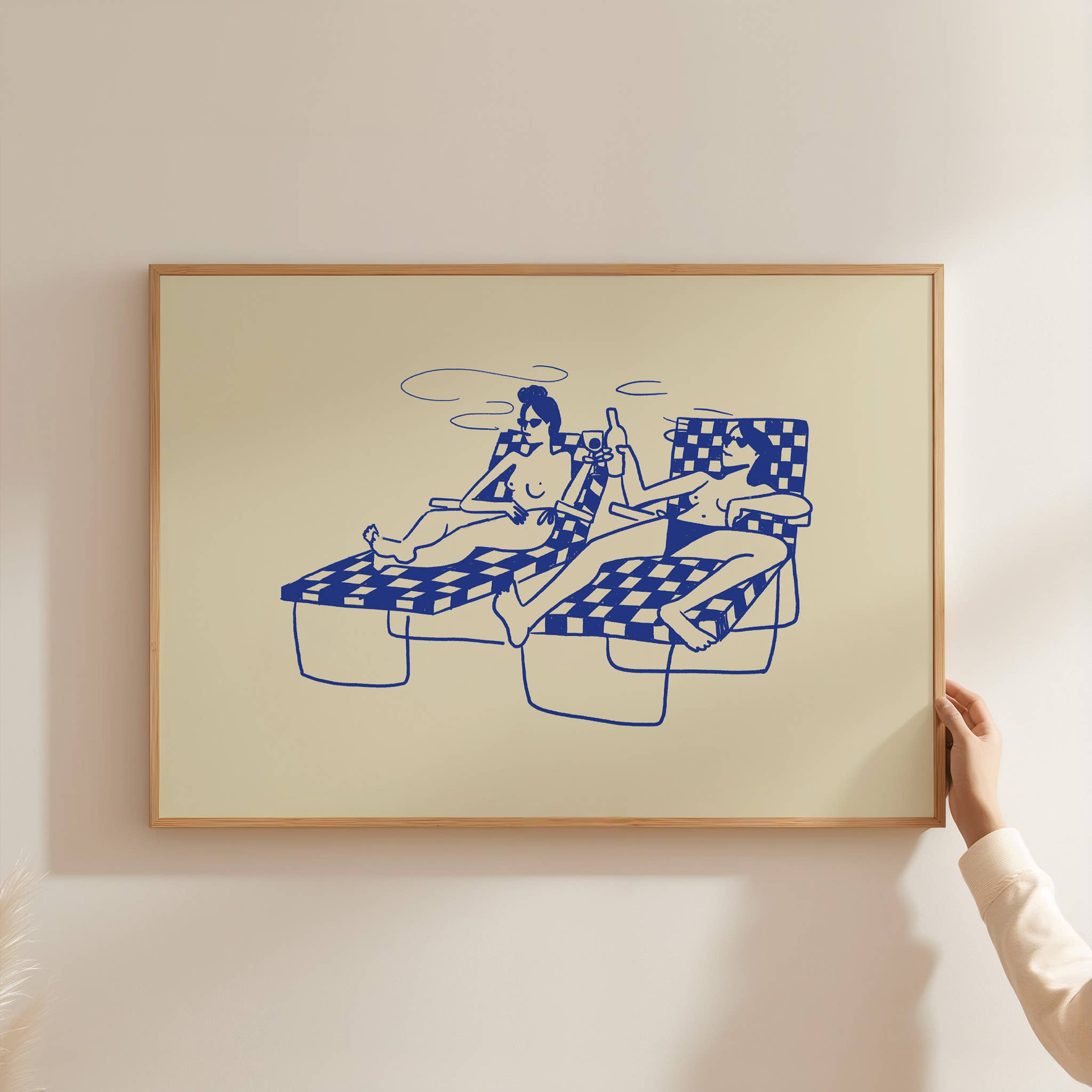 This piece of art feels like a mini-vacation. This unframed art print captures a delightful moment of two ladies basking in the sun by the pool, sipping cocktails and wine. With a soft butter yellow background and dark blue line drawing, it's a wonderfully relaxing piece of wall art that brings a touch of summer fun to any home decor collection.
