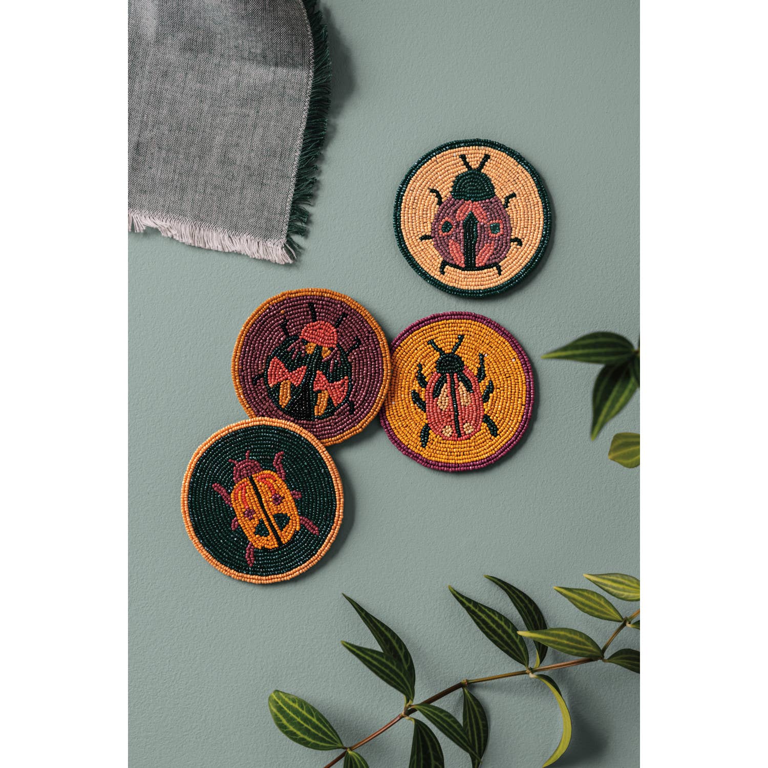 Set of 4 beaded coasters featuring unique beetle designs from Danica Studio’s Amulet collection. Made with glass beads and durable fabric for everyday use.