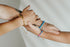 Two wrists wearing ceramic bead leather bracelets in gold and blue tones