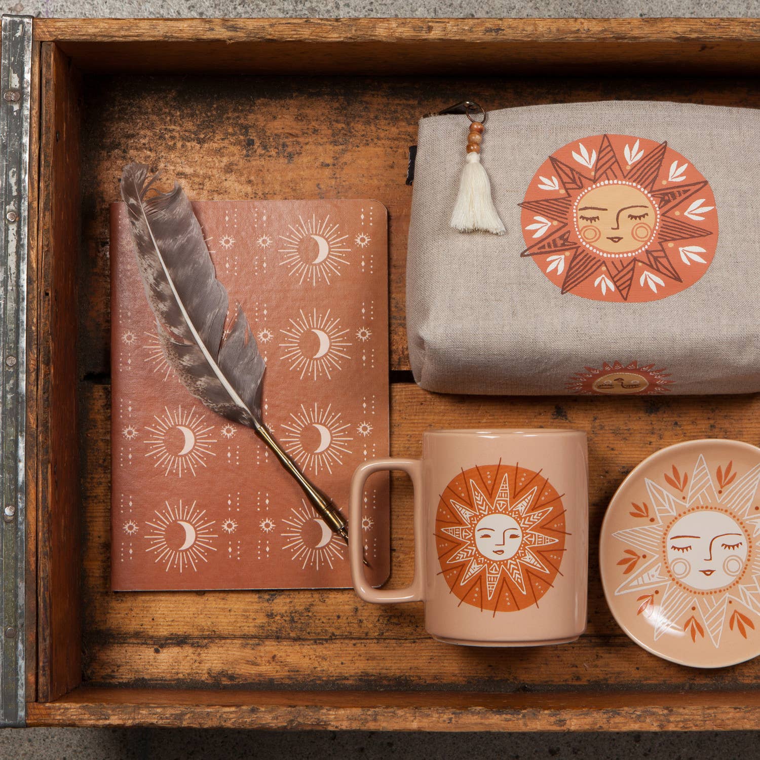 Decorative set with a mug, notebook, pouch, and dish featuring sun and moon designs on a wooden surface.