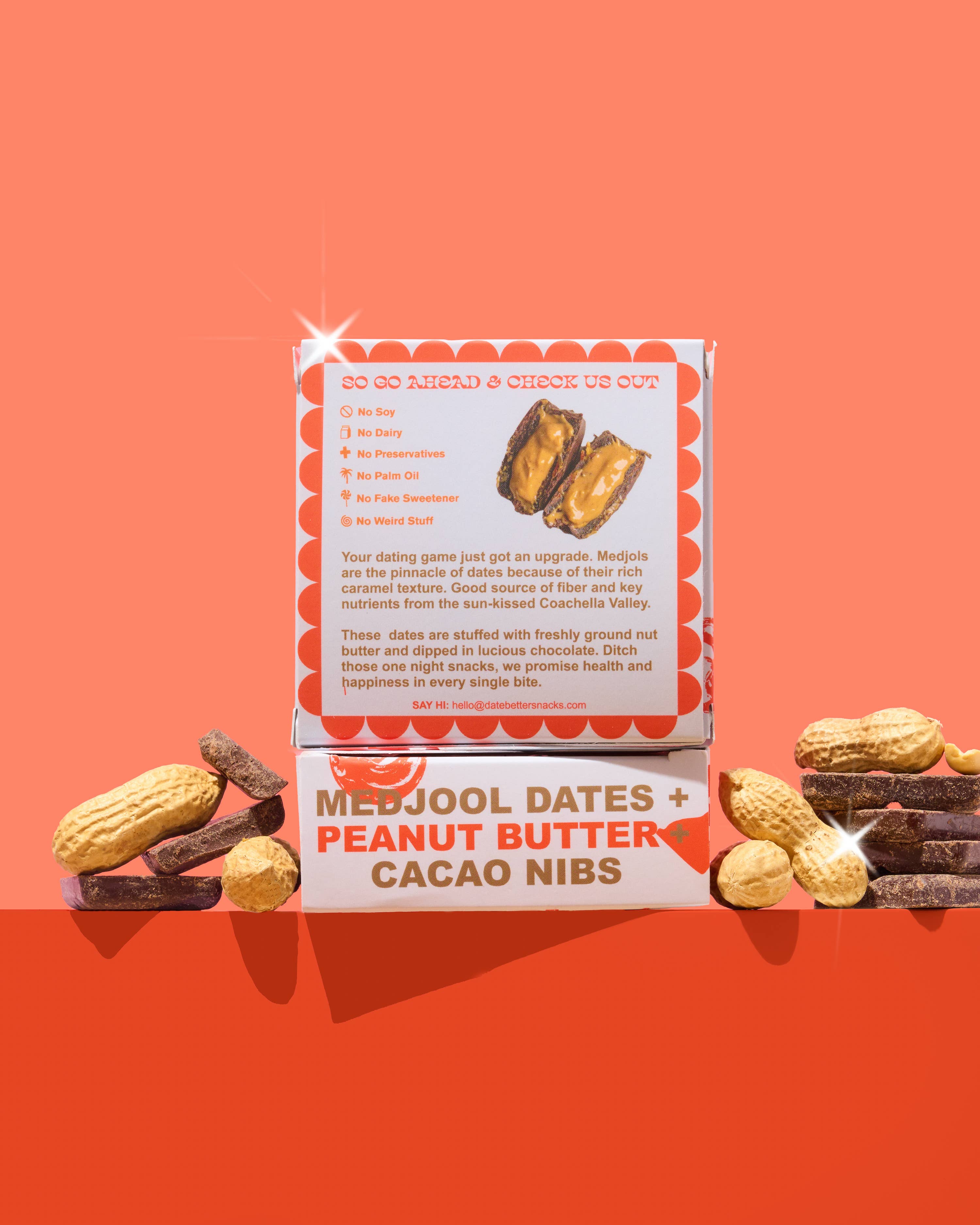 Box of Medjool dates, peanut butter, and cacao nibs on an orange background