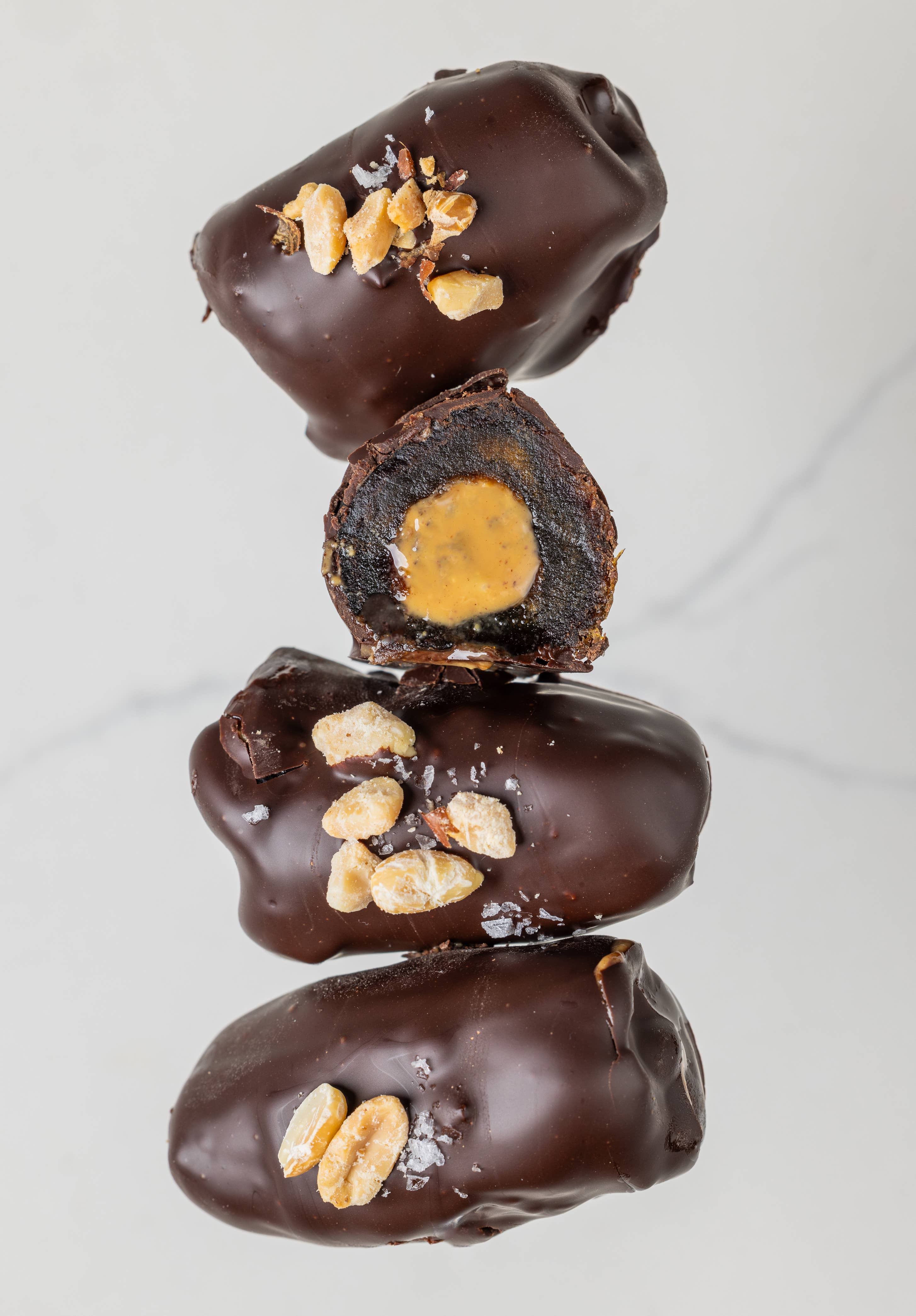 Stack of chocolate-covered treats with a visible filling on a light background