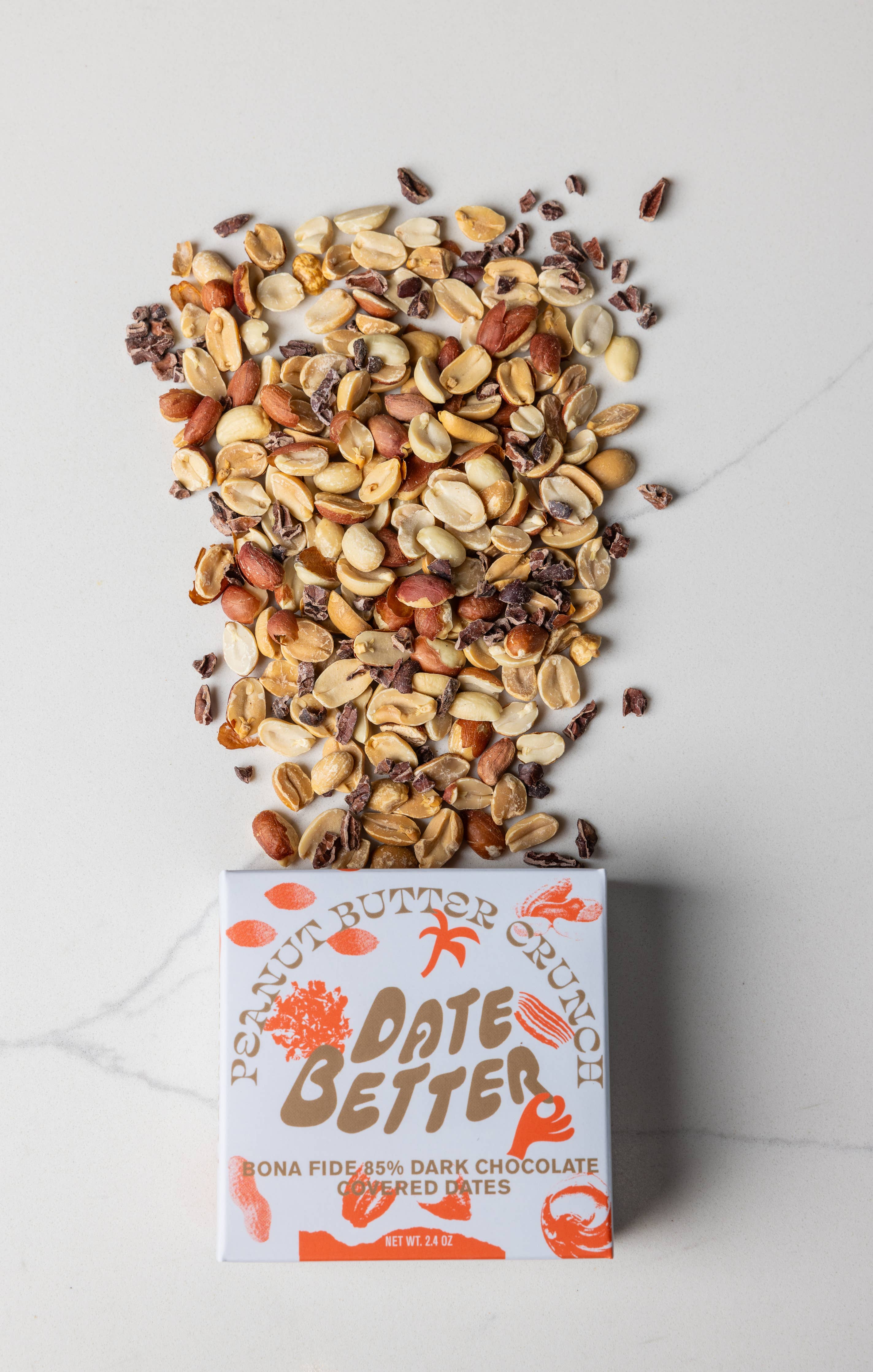 Box of Date Better chocolate with a scattering of nuts and seeds on a light background