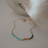 Dusk bracelet with turquoise and amber glass beads on a gold chain, on a light surface