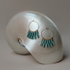 Pair of Dusk fringe hoops with teal glass bead fringe resting on a nautilus shell