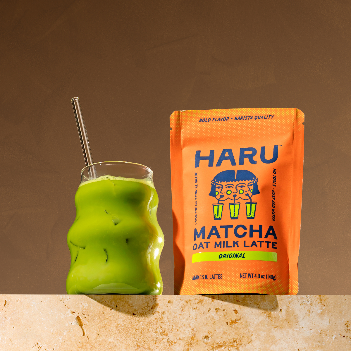 Green matcha oat milk latte in a glass with a Haru Matcha oat milk latte package on a brown background