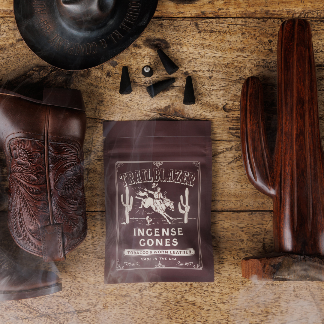 Pack of Trailblazer Incense Cones on a wooden surface with cowboy boot, cactus, and hat.
