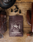 Pack of Trailblazer Incense Cones on a wooden surface with cowboy boot, cactus, and hat.