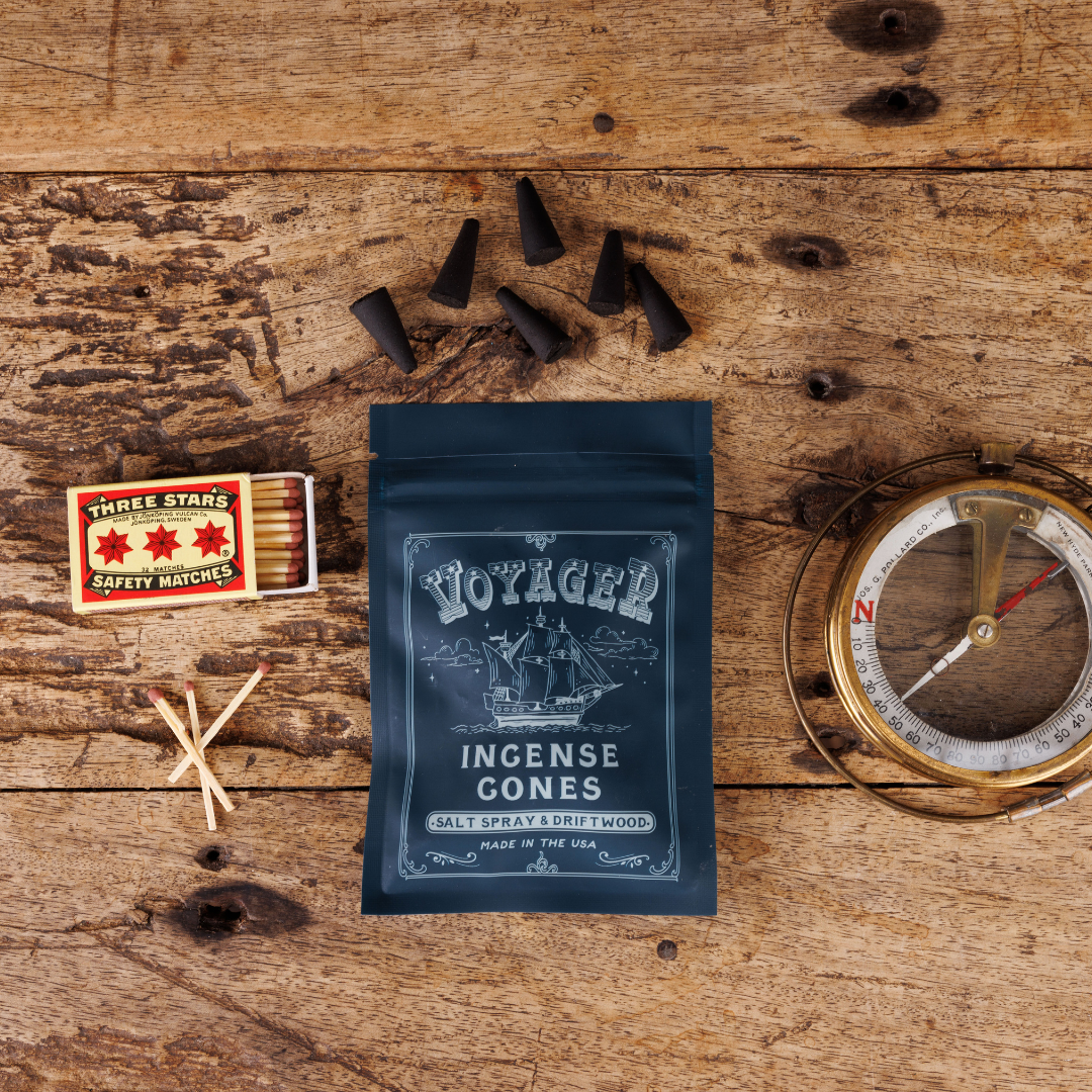 Voyaged Incense Cones packaging on a wooden surface with matches and a compass.