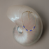 Gold-filled chain bracelet with blue and cream glass beads draped on a nautilus shell
