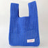 Bright blue open-weave knit shoulder bag on a white backdrop