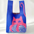 Blue knit shoulder bag with a pink cat on a ball of yarn, on a white backdrop