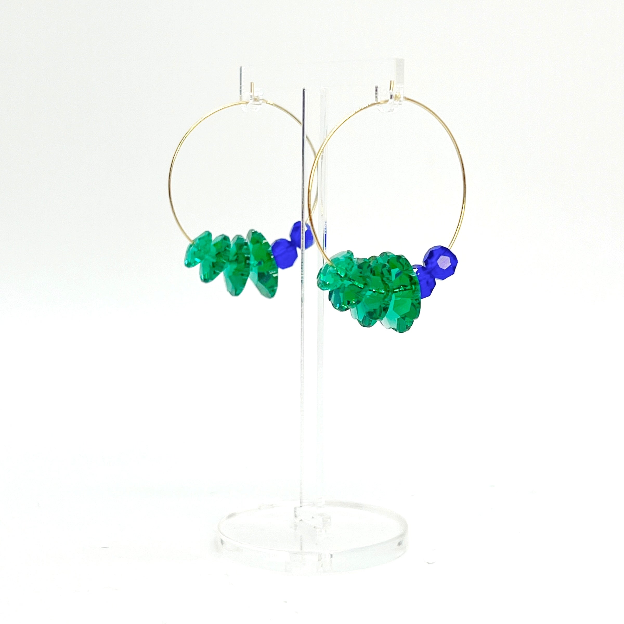 Designed with sculptural flow and oceanic calm, the Large Anchor Hoops feature descending teal floral crystals that create a cascading shape. Finished with two rich cobalt stones for balance, these hoops embody a quiet strength and grounded beauty that stands out without shouting.