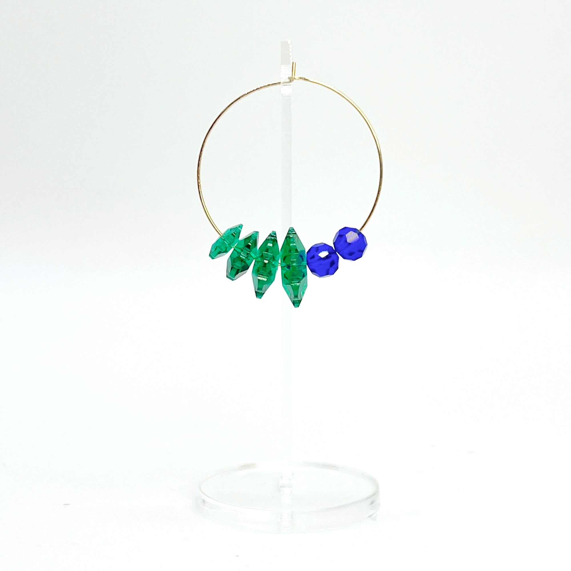 Designed with sculptural flow and oceanic calm, the Large Anchor Hoops feature descending teal floral crystals that create a cascading shape. Finished with two rich cobalt stones for balance, these hoops embody a quiet strength and grounded beauty that stands out without shouting.