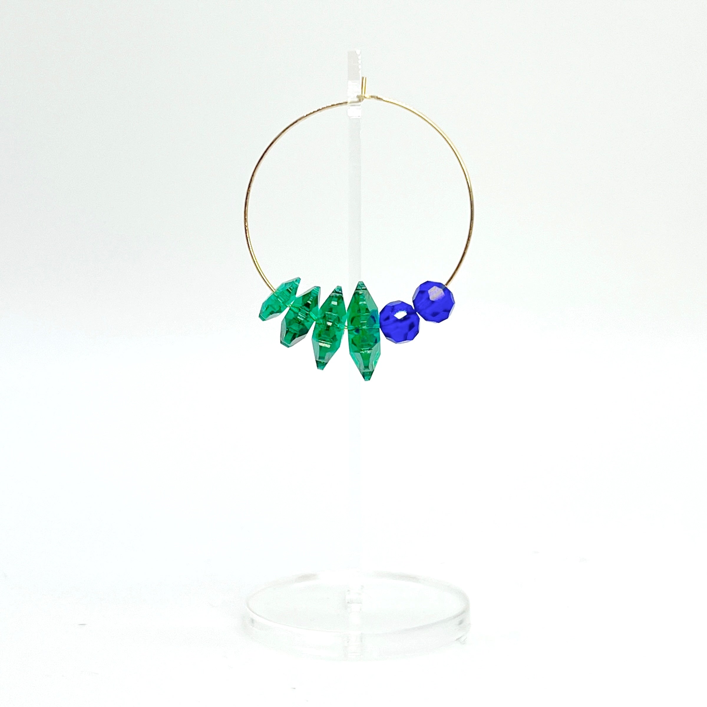 Designed with sculptural flow and oceanic calm, the Large Anchor Hoops feature descending teal floral crystals that create a cascading shape. Finished with two rich cobalt stones for balance, these hoops embody a quiet strength and grounded beauty that stands out without shouting.