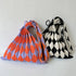 Pleated knit shoulder bags in orange and lavender and black and white diamond patterns