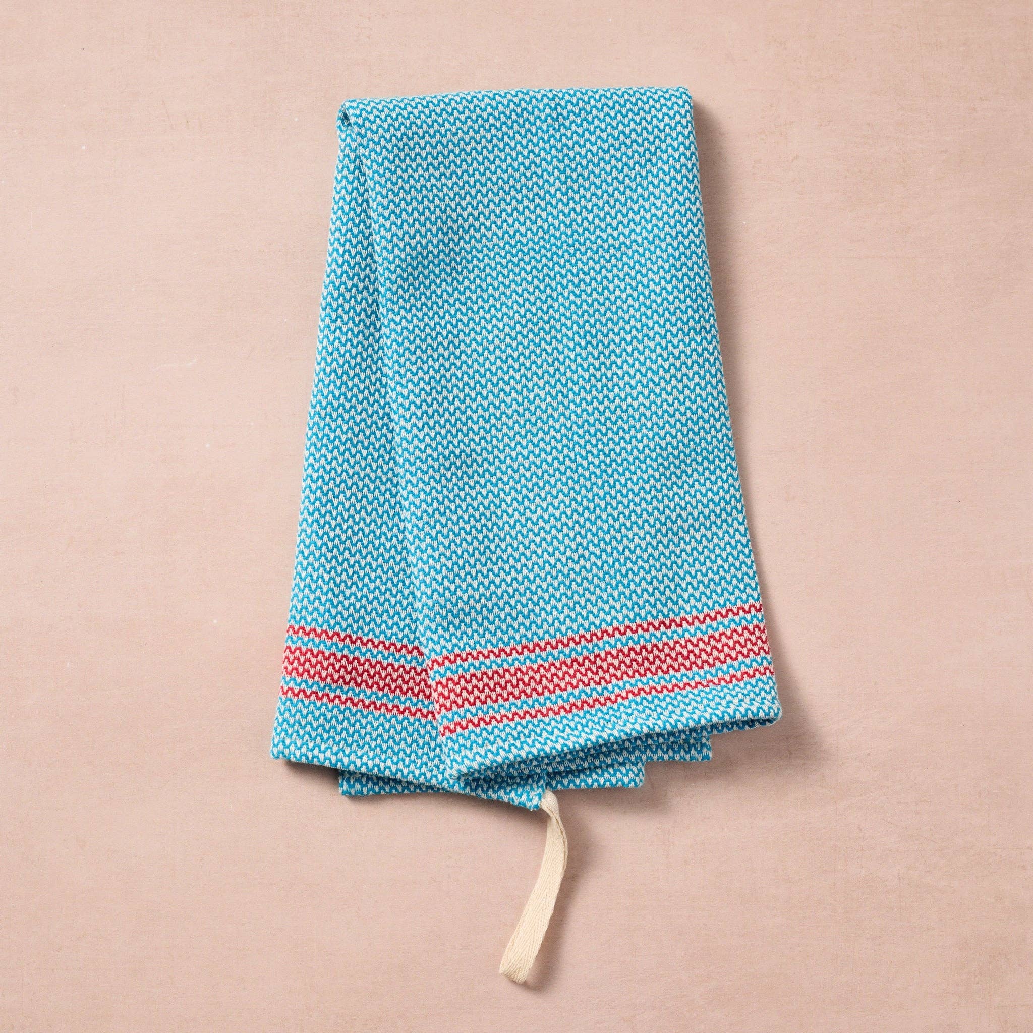 Brighten your kitchen with a pop of color and timeless charm. This striped woven tea towel blends function with simple elegance, featuring a refreshing aqua and white base accented by three bold red stripes at each end. Crafted from 100% cotton, it’s soft, absorbent and ready to tackle daily tasks - from drying dishes to lining a breadbasket. A convenient cotton loop in the corner makes it easy to hang and display. Whether you’re cooking up memories or cleaning up spills, this towel adds a cheerful, artisan