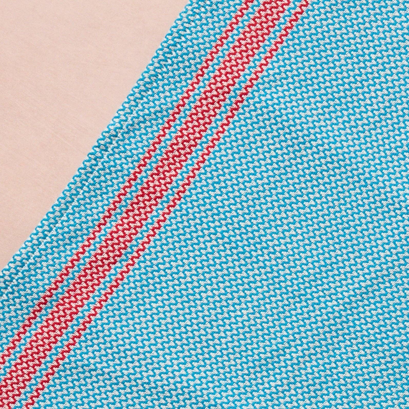 Brighten your kitchen with a pop of color and timeless charm. This striped woven tea towel blends function with simple elegance, featuring a refreshing aqua and white base accented by three bold red stripes at each end. Crafted from 100% cotton, it’s soft, absorbent and ready to tackle daily tasks - from drying dishes to lining a breadbasket. A convenient cotton loop in the corner makes it easy to hang and display. Whether you’re cooking up memories or cleaning up spills, this towel adds a cheerful, artisan