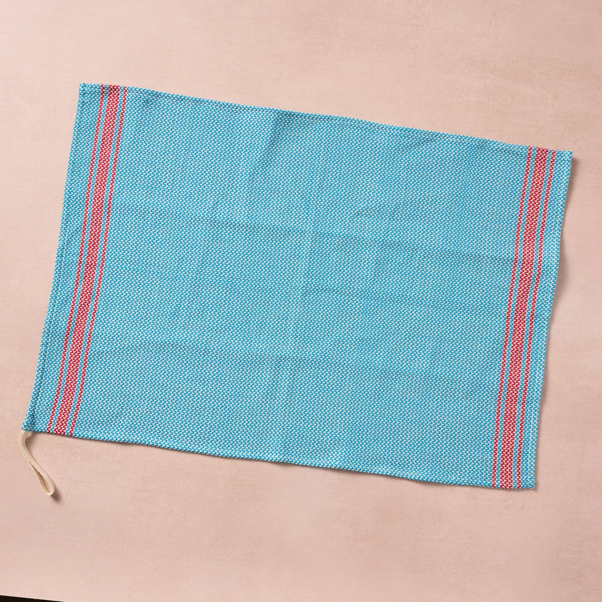Brighten your kitchen with a pop of color and timeless charm. This striped woven tea towel blends function with simple elegance, featuring a refreshing aqua and white base accented by three bold red stripes at each end. Crafted from 100% cotton, it’s soft, absorbent and ready to tackle daily tasks - from drying dishes to lining a breadbasket. A convenient cotton loop in the corner makes it easy to hang and display. Whether you’re cooking up memories or cleaning up spills, this towel adds a cheerful, artisan