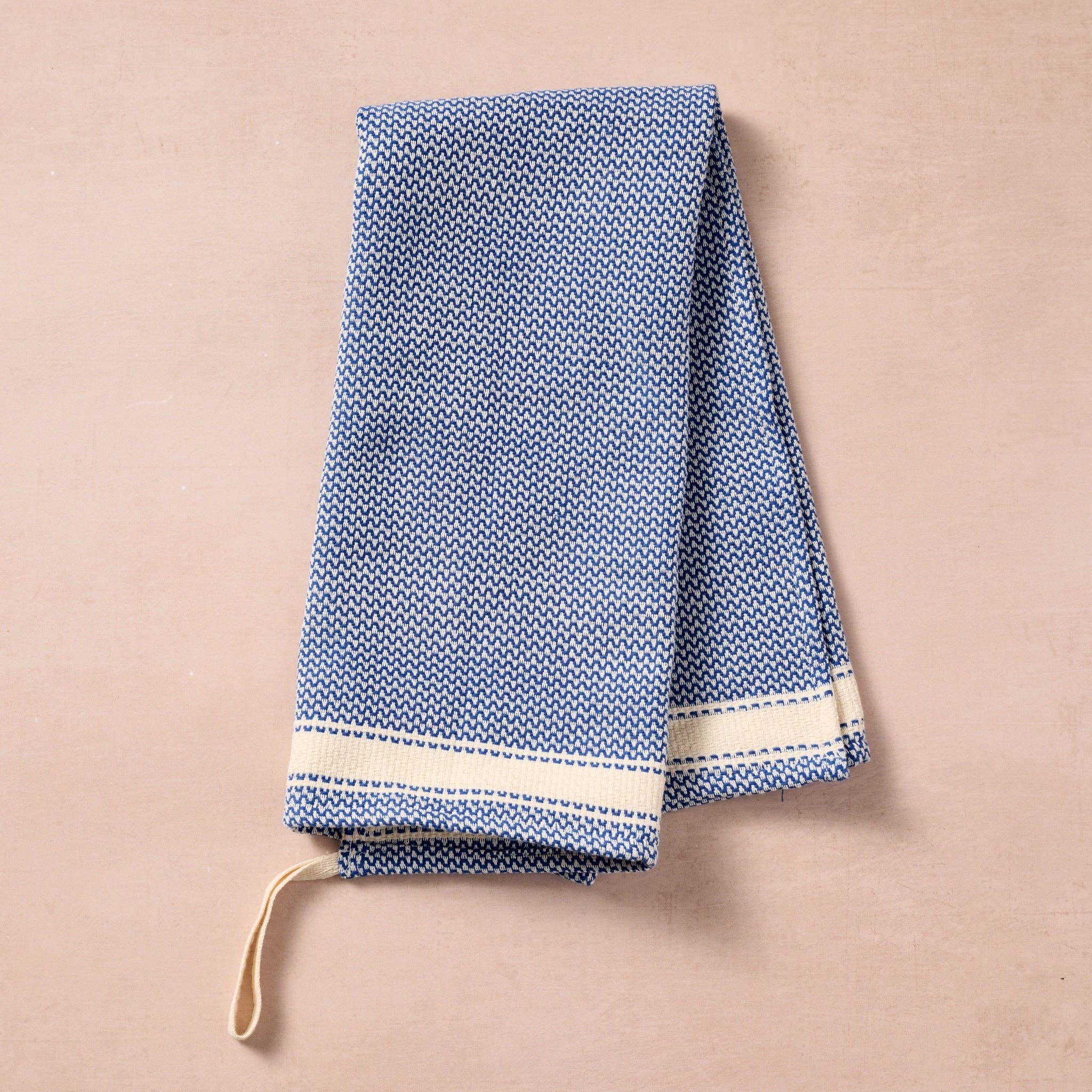 Brighten your kitchen with a pop of color and timeless charm. This striped woven tea towel blends function with simple elegance, featuring a refreshing blue and white base accented by three bold tan stripes at each end. Crafted from 100% cotton, it’s soft, absorbent and ready to tackle daily tasks - from drying dishes to lining a breadbasket. A convenient cotton loop in the corner makes it easy to hang and display. Whether you’re cooking up memories or cleaning up spills, this towel adds a cheerful, artisan
