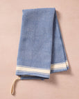 Brighten your kitchen with a pop of color and timeless charm. This striped woven tea towel blends function with simple elegance, featuring a refreshing blue and white base accented by three bold tan stripes at each end. Crafted from 100% cotton, it’s soft, absorbent and ready to tackle daily tasks - from drying dishes to lining a breadbasket. A convenient cotton loop in the corner makes it easy to hang and display. Whether you’re cooking up memories or cleaning up spills, this towel adds a cheerful, artisan