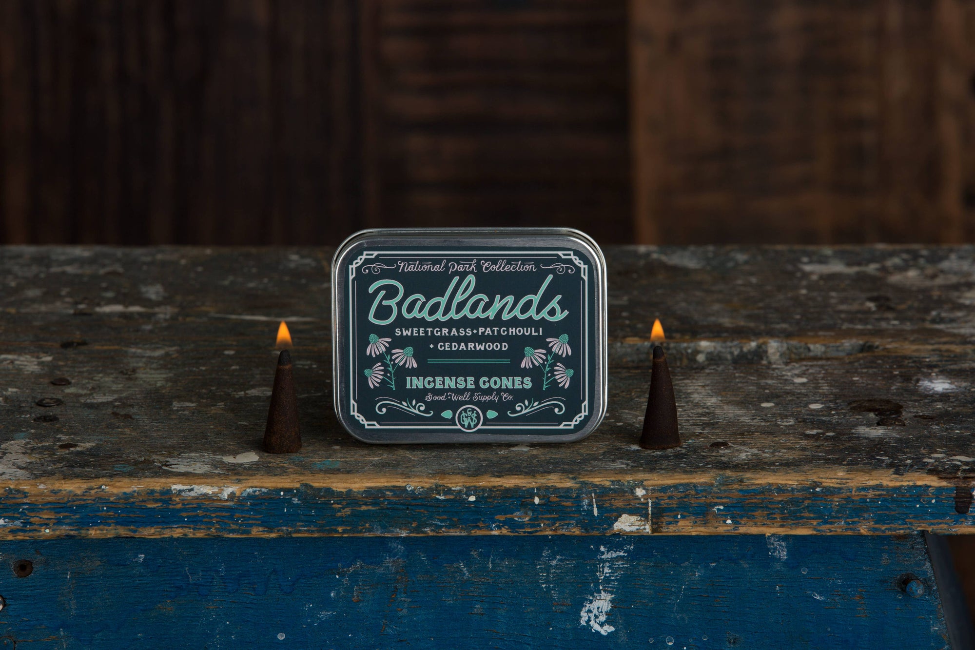 Badlands incense cones packaging with two lit incense cones on a rustic wooden surface.