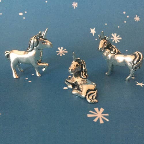 Three silver unicorn charms on a blue background with star patterns