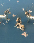 Three silver unicorn charms on a blue background with star patterns