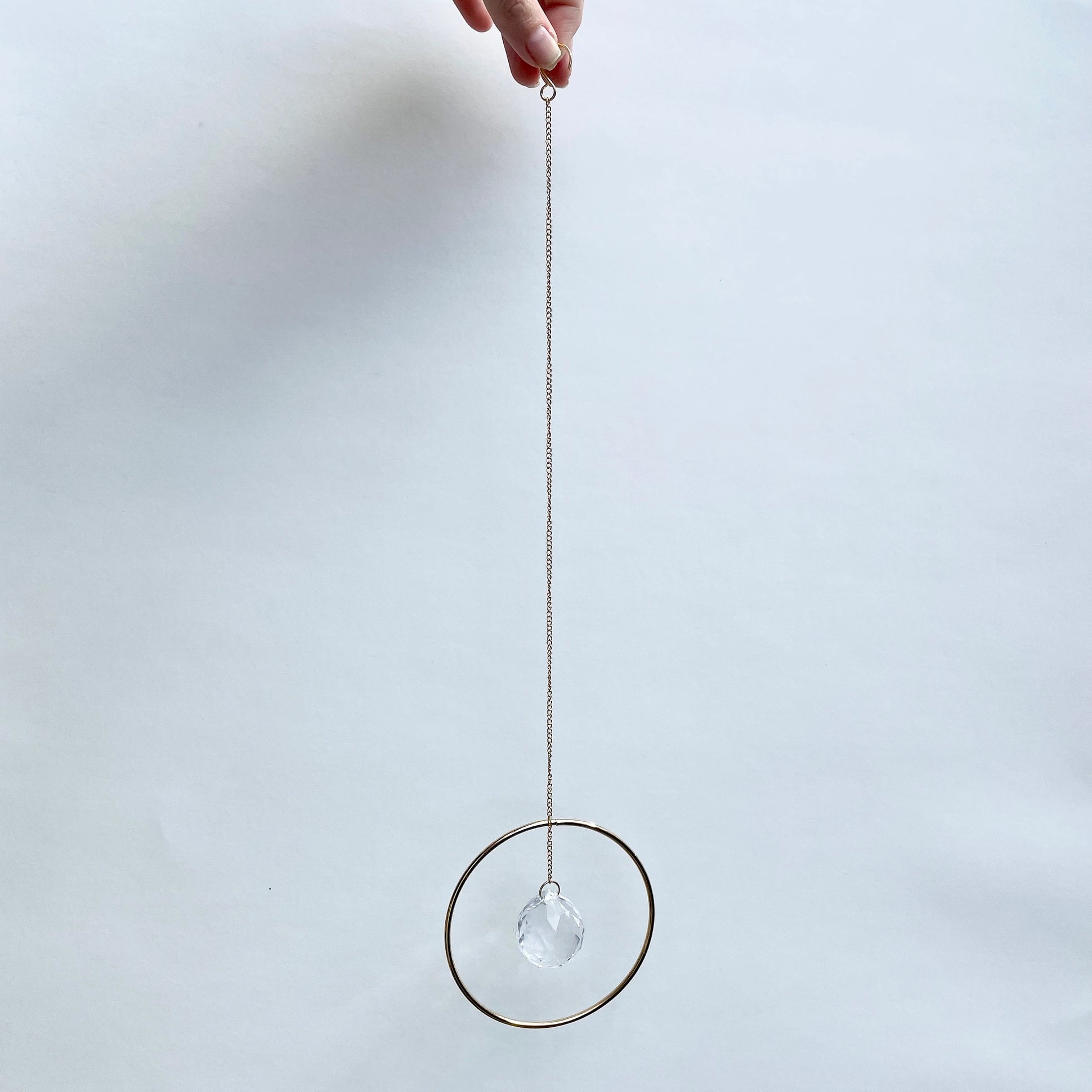 Bring a little sparkle and magic into your home with Prism Ring Suncatchers. Each piece features a golden ring with a prism suspended at its center, designed to catch sunlight and scatter tiny rainbows across your walls and floors. Hang it in a bright window or on a wall to add a touch of light-filled beauty to your space.