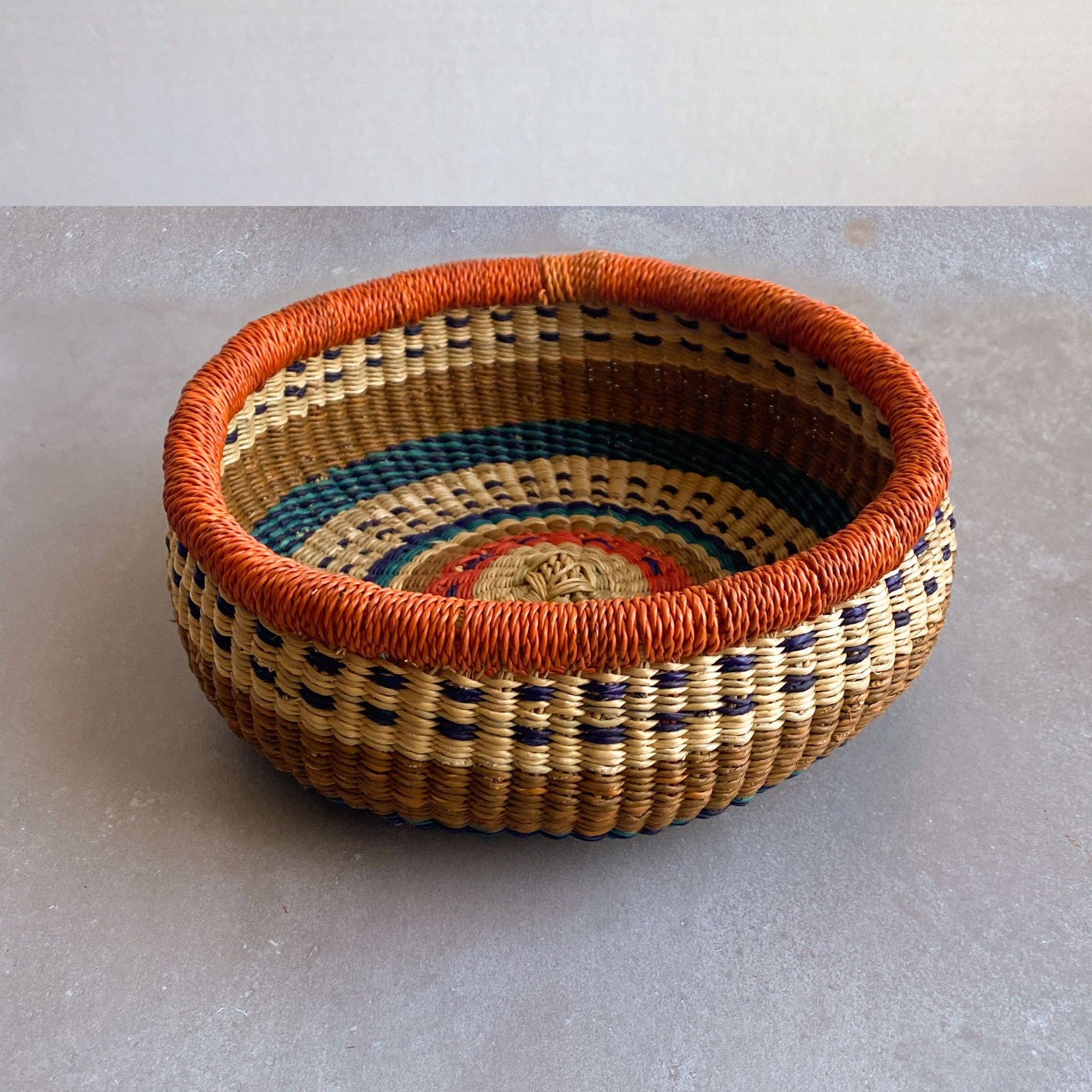 Decorate your home with a Round Bolga Basket, handwoven by experienced women in Ghana's Bolgatanga region using locally sourced veta vera grass. Each basket is woven wet and can be re-shaped by adding water. Durable and washable, these baskets are a beautiful and unique addition to your decor. Fun fact: kinkahe is a local name for veta vera grass in Ghana!