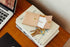 Natural leather Nan wallet with keys on a stack of books beside a laptop