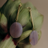 Gold-tone bar earrings with round purple lepidolite stones resting on green leaves