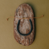 Black ceramic bead bracelet on a leather cord laid on bark against olive green