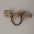 Tiger eye bead bracelet hanging on a piece of driftwood against a gray wall