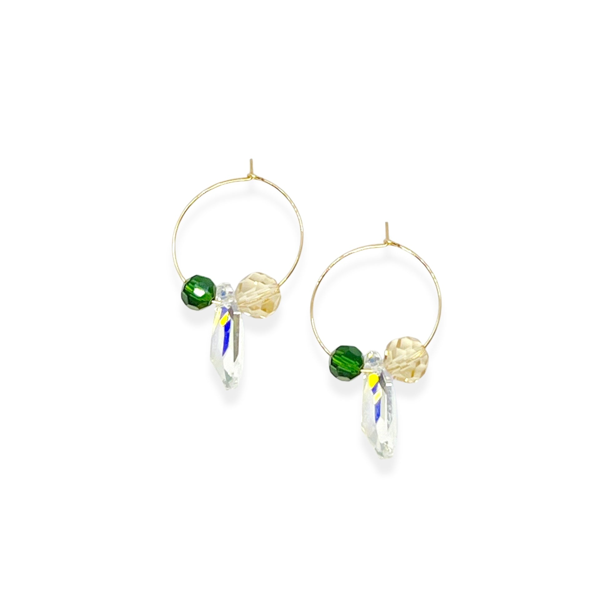 Understated elegance with a twist. The Small Muse Hoops combine a soft champagne crystal and a rich emerald green stone to frame an asymmetrical feature crystal at the center. The result is a beautifully balanced mix of refinement and individuality—perfect for the quietly powerful.