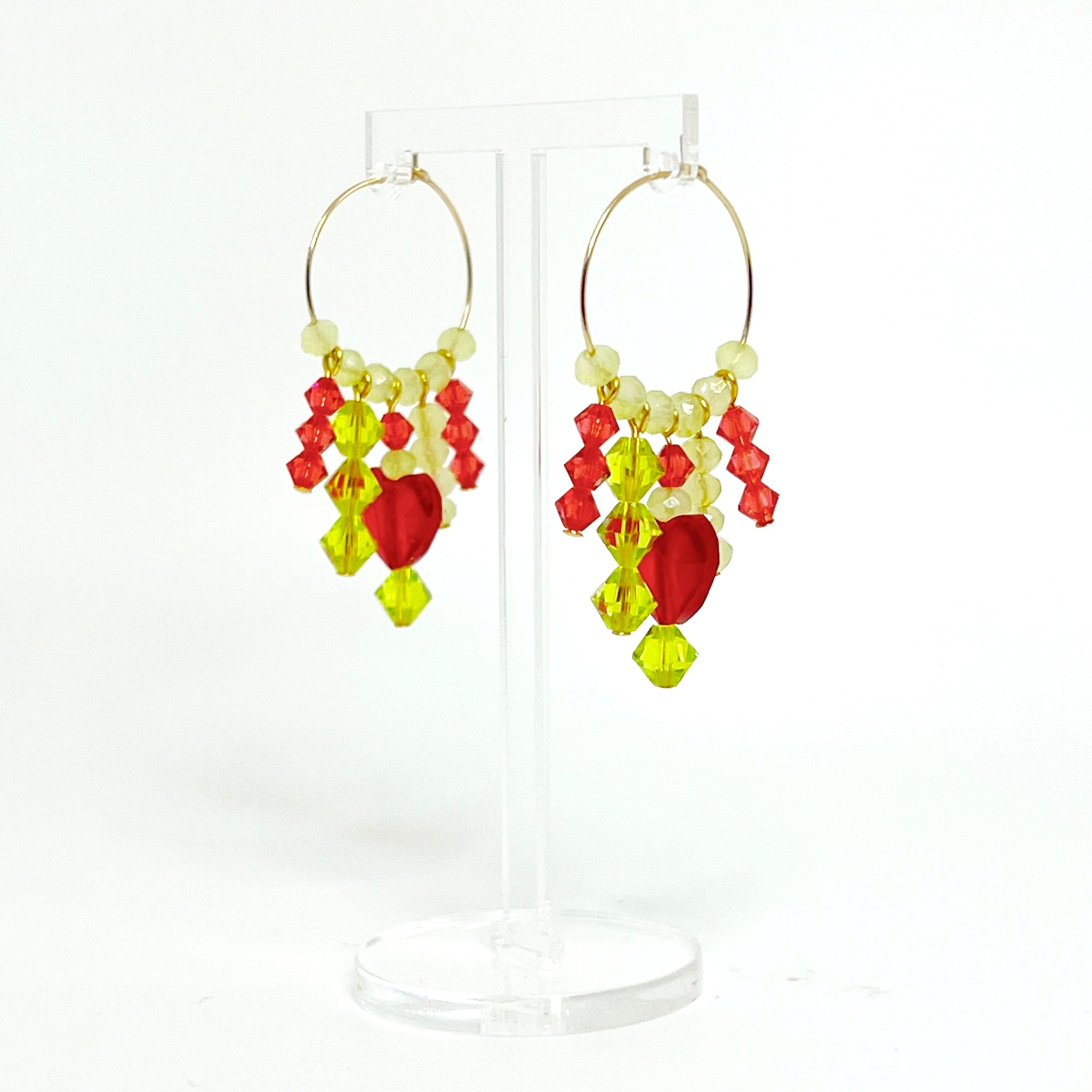 Joyful, flirty, and full of energy—these Small Spark Hoops are a burst of personality. A radiant heart-shaped crystal takes center stage, framed by watermelon and chartreuse tones that feel like summer bottled up. A scattering of dangling crystals adds playful movement, making these hoops perfect for anyone who loves to stand out and shine.