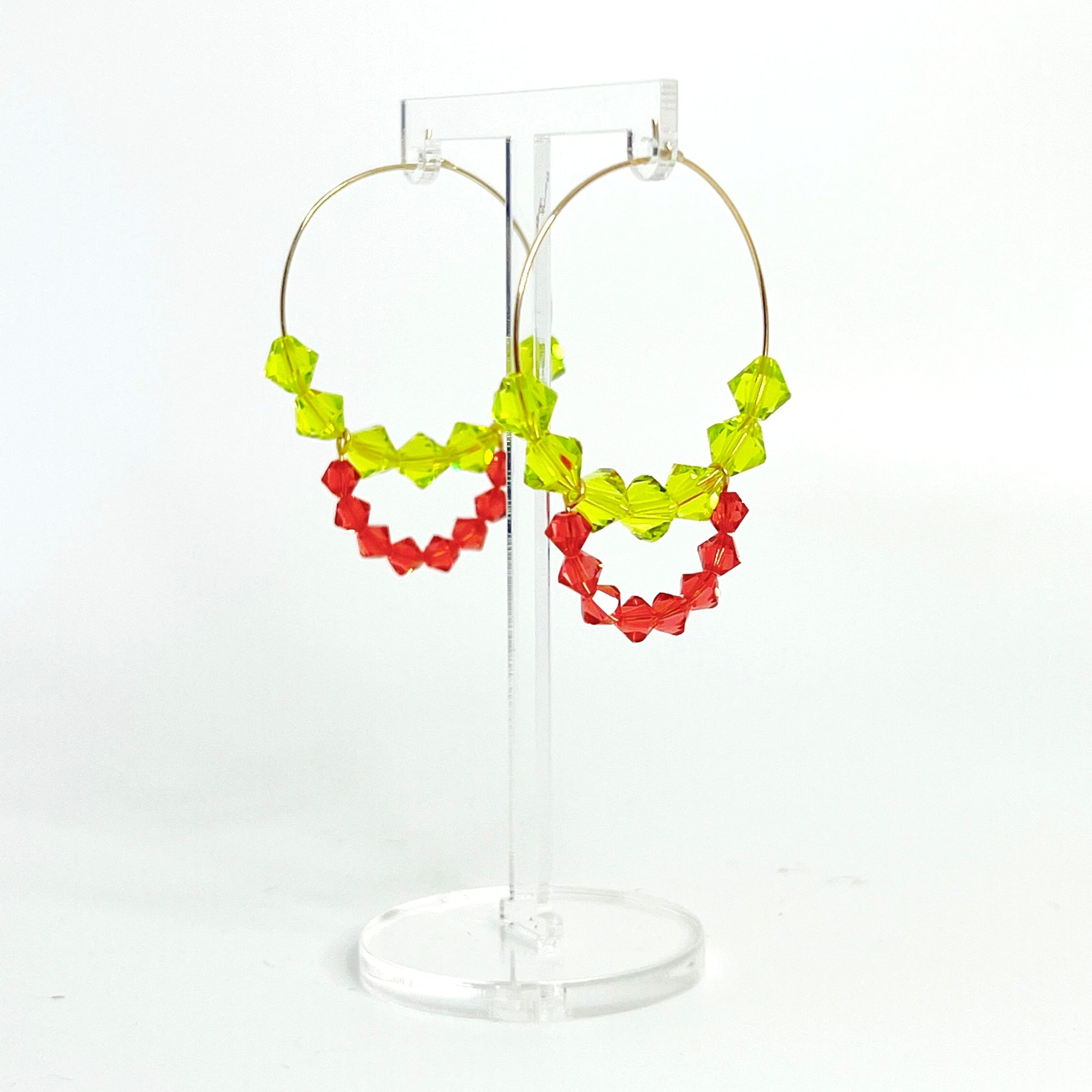 Joyful, flirty, and full of energy—these Small Spark Hoops are a burst of personality. A radiant heart-shaped crystal takes center stage, framed by watermelon and chartreuse tones that feel like summer bottled up. A scattering of dangling crystals adds playful movement, making these hoops perfect for anyone who loves to stand out and shine.