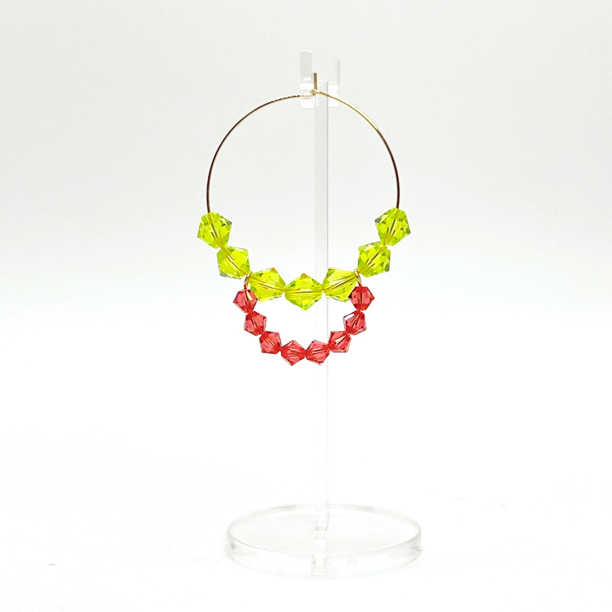 Joyful, flirty, and full of energy—these Small Spark Hoops are a burst of personality. A radiant heart-shaped crystal takes center stage, framed by watermelon and chartreuse tones that feel like summer bottled up. A scattering of dangling crystals adds playful movement, making these hoops perfect for anyone who loves to stand out and shine.