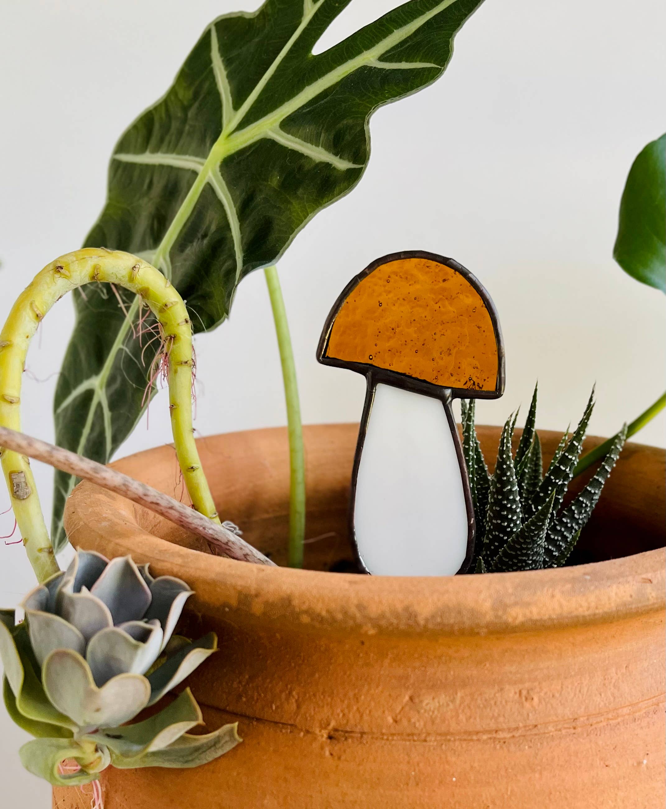 Handcrafted amber stained glass mushroom adds charm to plants or gardens. Weatherproof and pet-safe. Perfect for unique home decor and garden gifts.