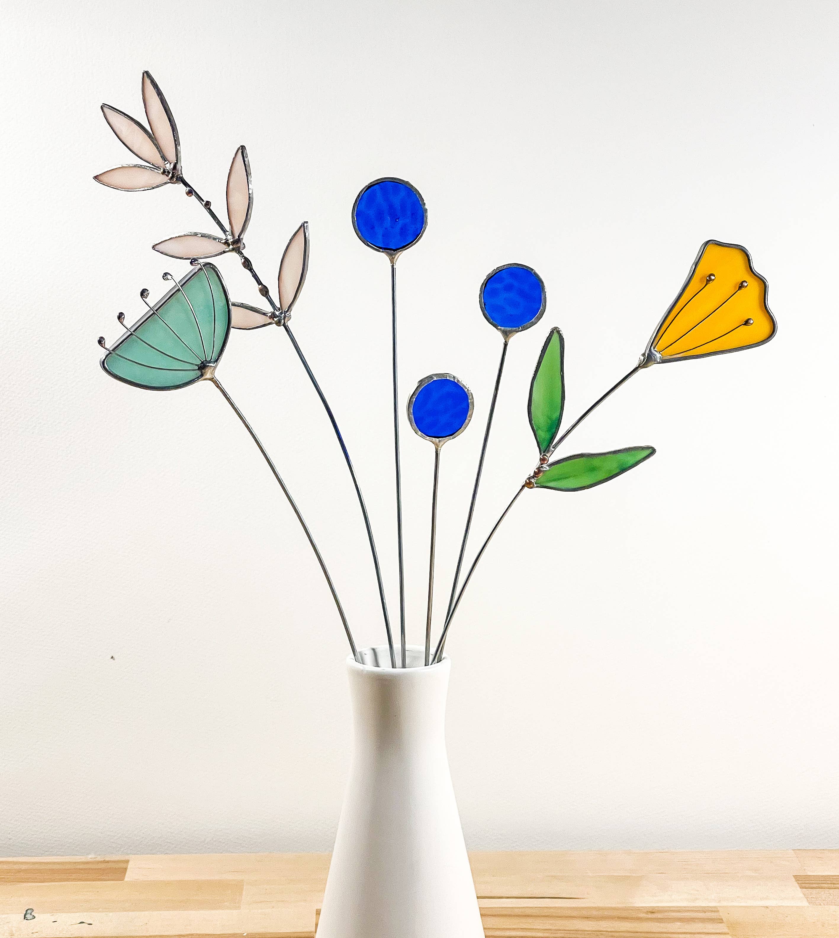 Bring a pop of color and artistry to your home with this handcrafted set of stained glass blue globe thistles by Samara Designs Studio. Each stem is carefully handmade using cobalt blue stained glass, cut and assembled with care to create a lasting botanical accent that will never wilt or fade.