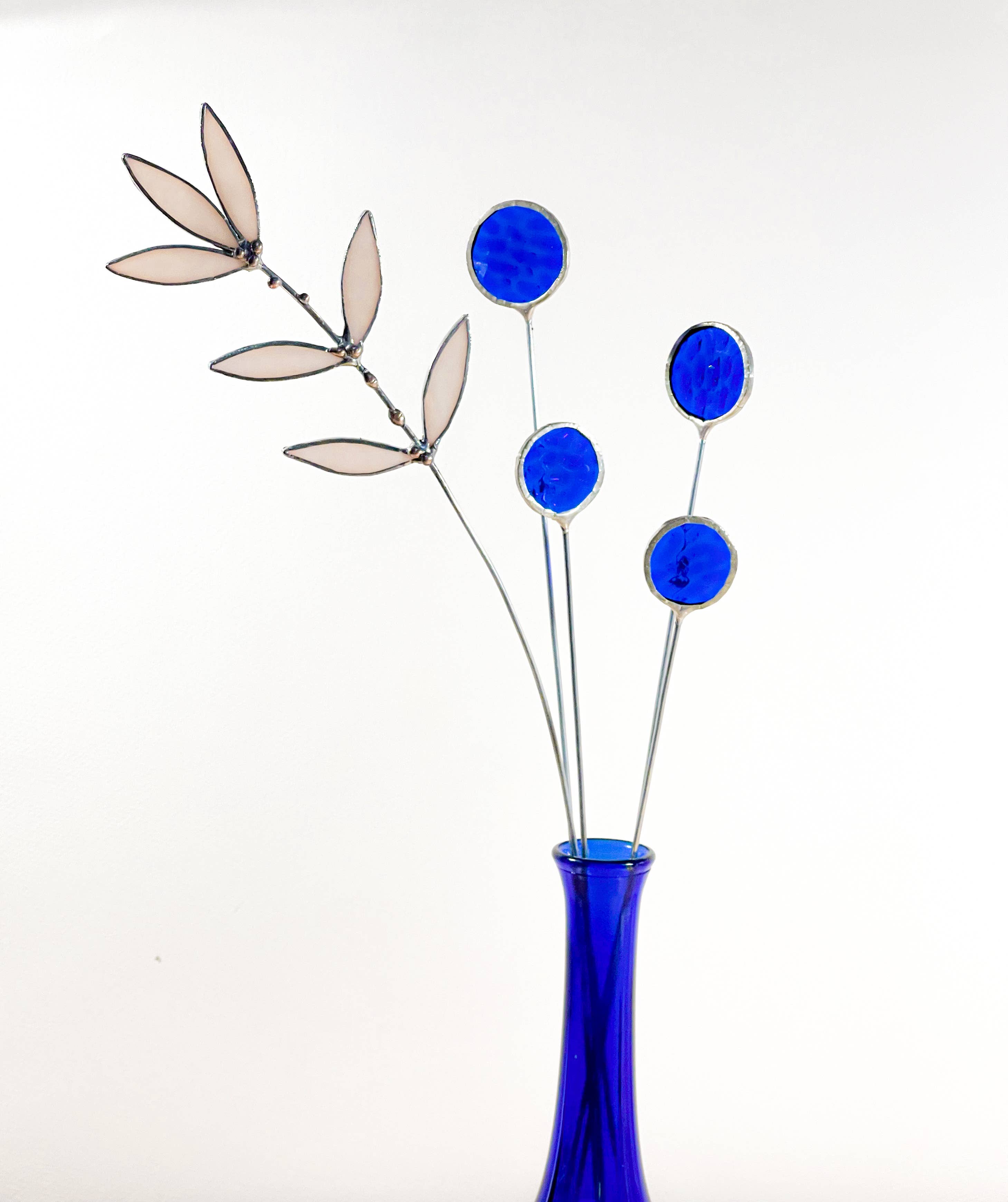 Bring a pop of color and artistry to your home with this handcrafted set of stained glass blue globe thistles by Samara Designs Studio. Each stem is carefully handmade using cobalt blue stained glass, cut and assembled with care to create a lasting botanical accent that will never wilt or fade.