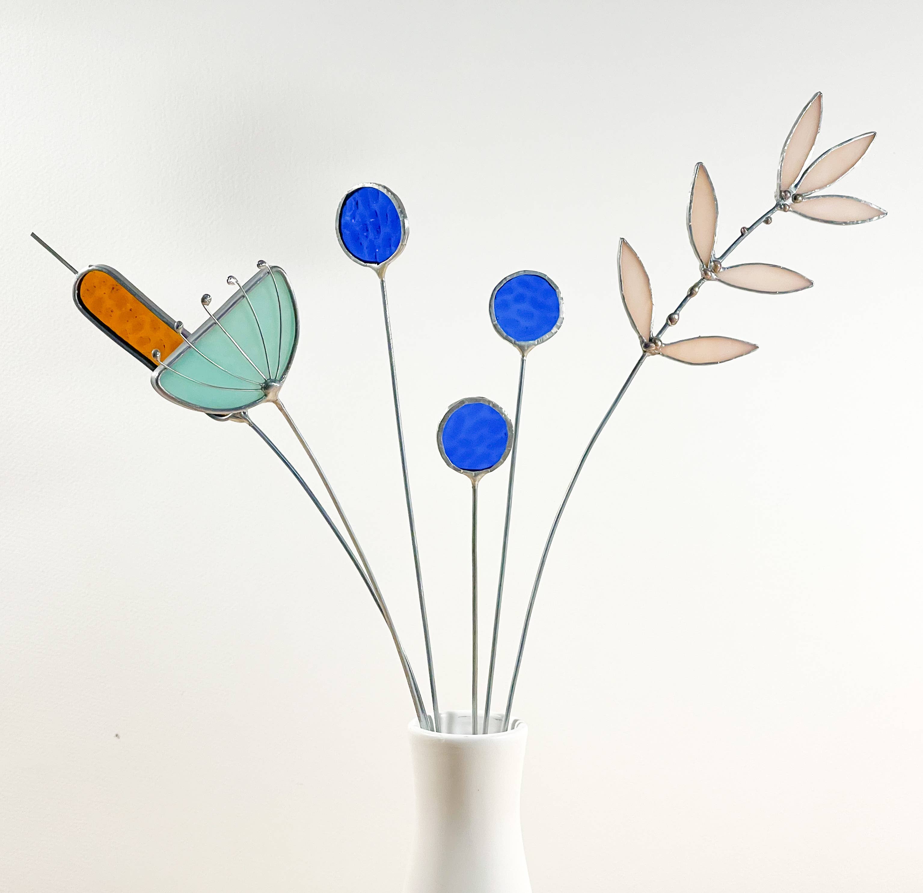 Bring a pop of color and artistry to your home with this handcrafted set of stained glass blue globe thistles by Samara Designs Studio. Each stem is carefully handmade using cobalt blue stained glass, cut and assembled with care to create a lasting botanical accent that will never wilt or fade.