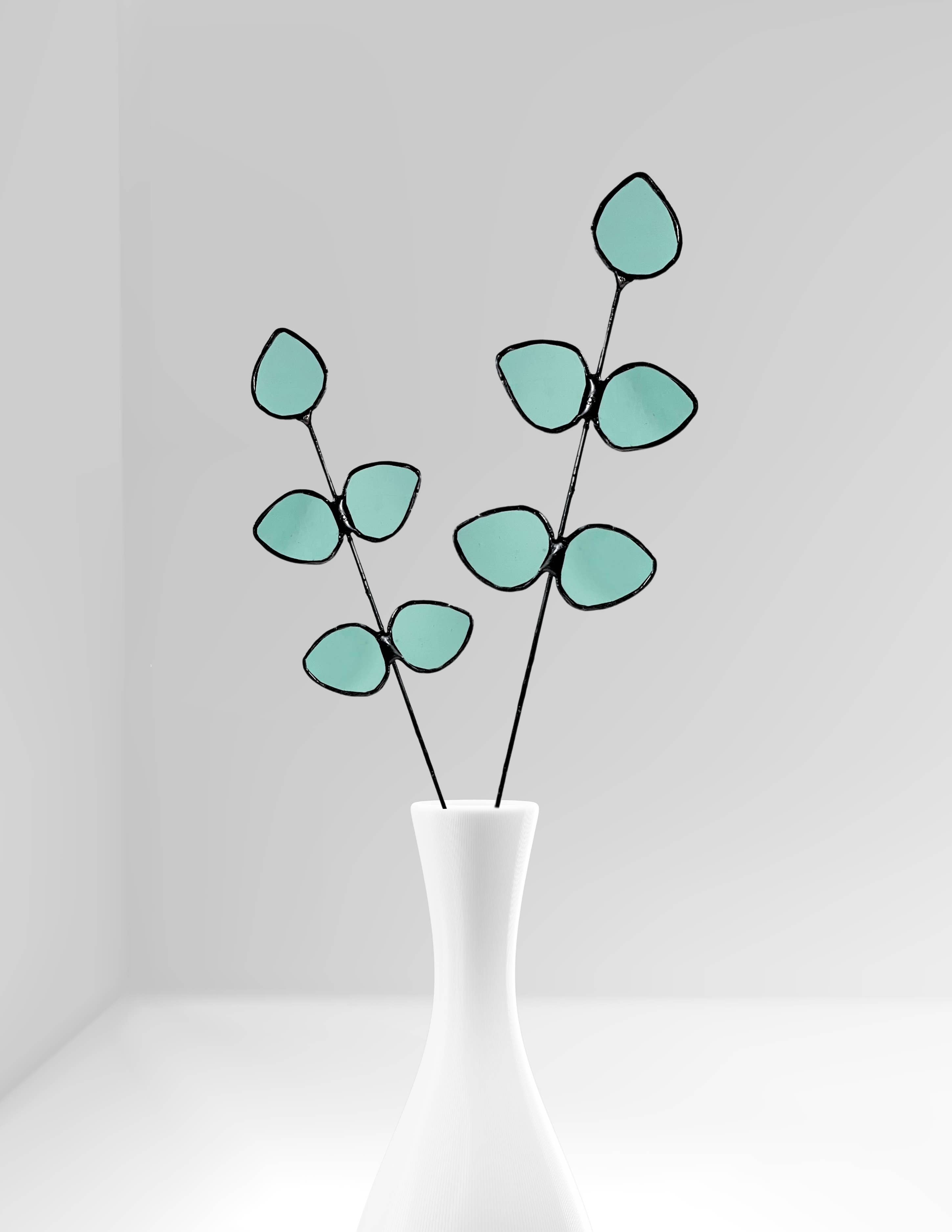 Bring a pop of color and artistry to your home with this handcrafted stained glass gumdrop eucalyptus stem by Samara Designs Studio. This stem is made from beautiful transparent seafoam green stained glass, cut and assembled by hand to create a lasting botanical accent that will never wilt or fade.